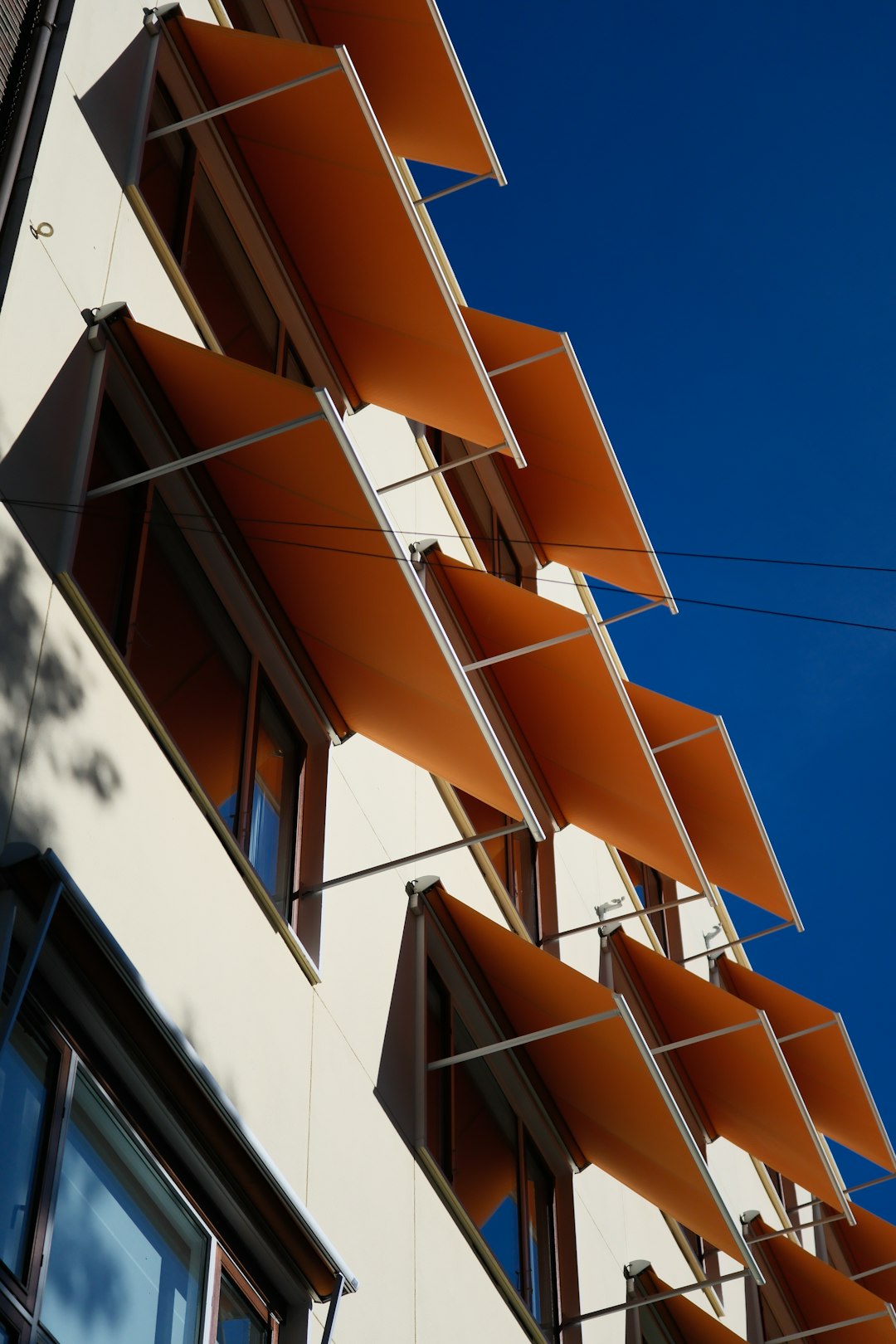 modern-building-with-orange-awnings-against-blue-sky-vuxzumet-am